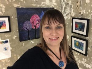 Kirsten Bailey in front of her paintings at the Heart Felt Exhibition