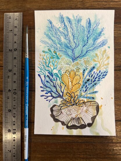 Image of a painting of a blue and gold reef in watercolour, next to a ruler and a paintbrush